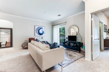 A living room with a white couch and a painting on the wall.